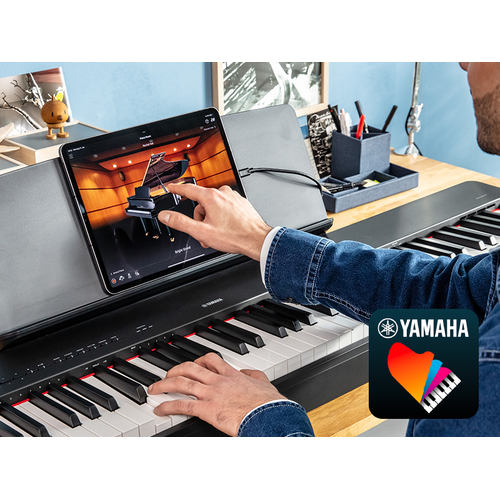 The Yamaha “Smart Pianist” app icon, together with a tablet placed on the m ature imageusic stand of the P-225
