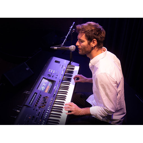 Man singing into microphone while playing Genos2
