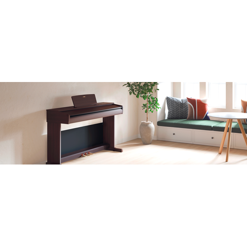 Một chiếc đàn piano ARIUS trong phòng khách với nắp đóng lại, hòa hợp với không gian nội thất.