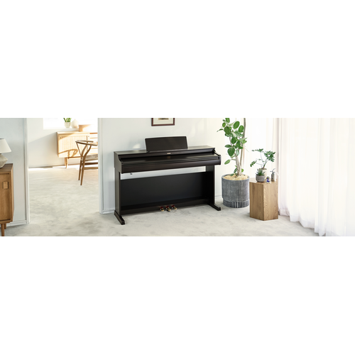 Một chiếc đàn piano ARIUS trong phòng khách với nắp đóng lại, hòa hợp với không gian nội thất.